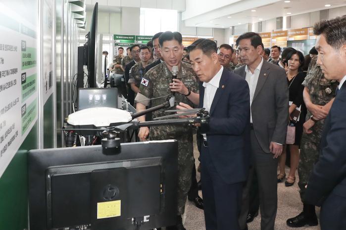Defense Minister Shin Won Sik (center) is briefed on on-device AI-based surveillance and reconnaissance system by Navy Col. Park Seong-je, head of the Joint Experiment Division of the Joint Chiefs of Staff, at an exhibition of major achievements in data and AI held on the first floor of the Defense 
